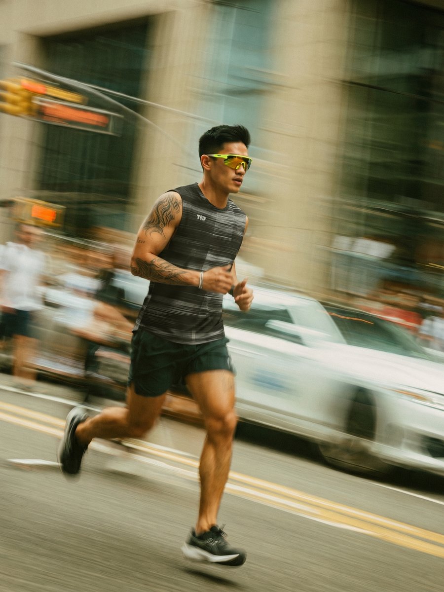 Man mid-stride running down a city street, motion-blurred traffic behind him.